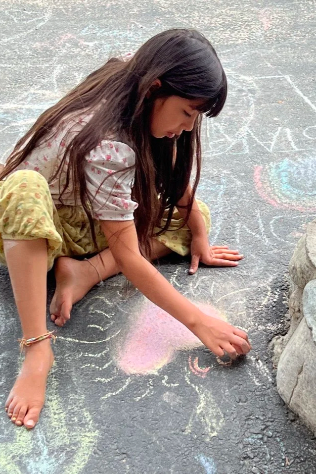Child drawing with chalk on a pavement