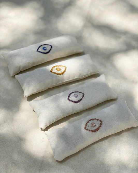 Five white pillows with embroidered designs on a light background