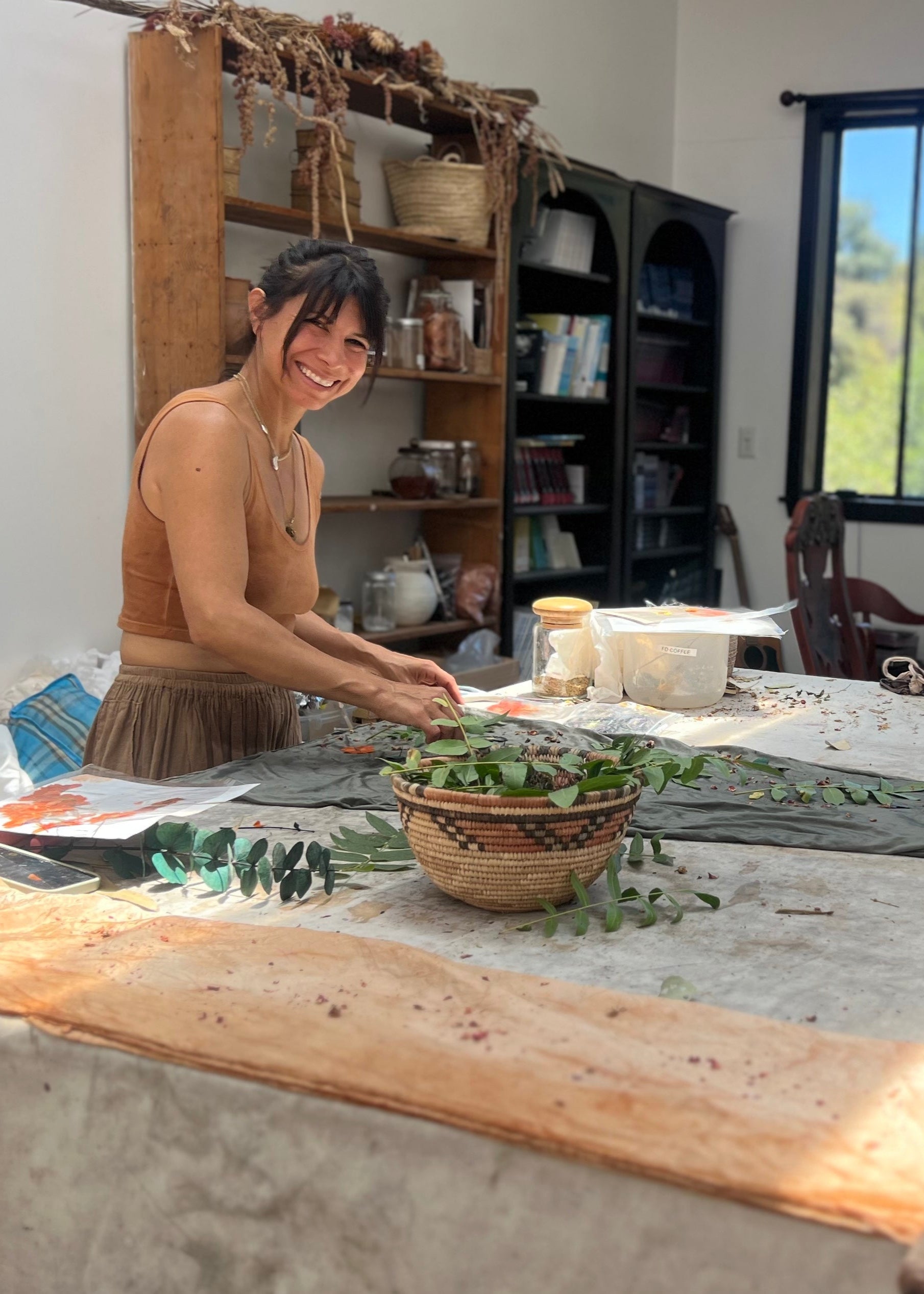 Woman preparing a garment for plant dyeing with a window in the background
