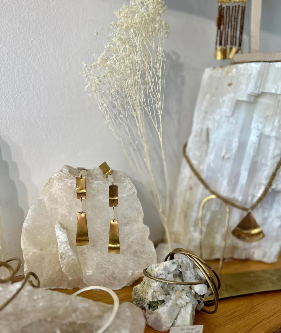 Decorative setting with crystal sculptures and gold handmade jewlery on a wooden surface.