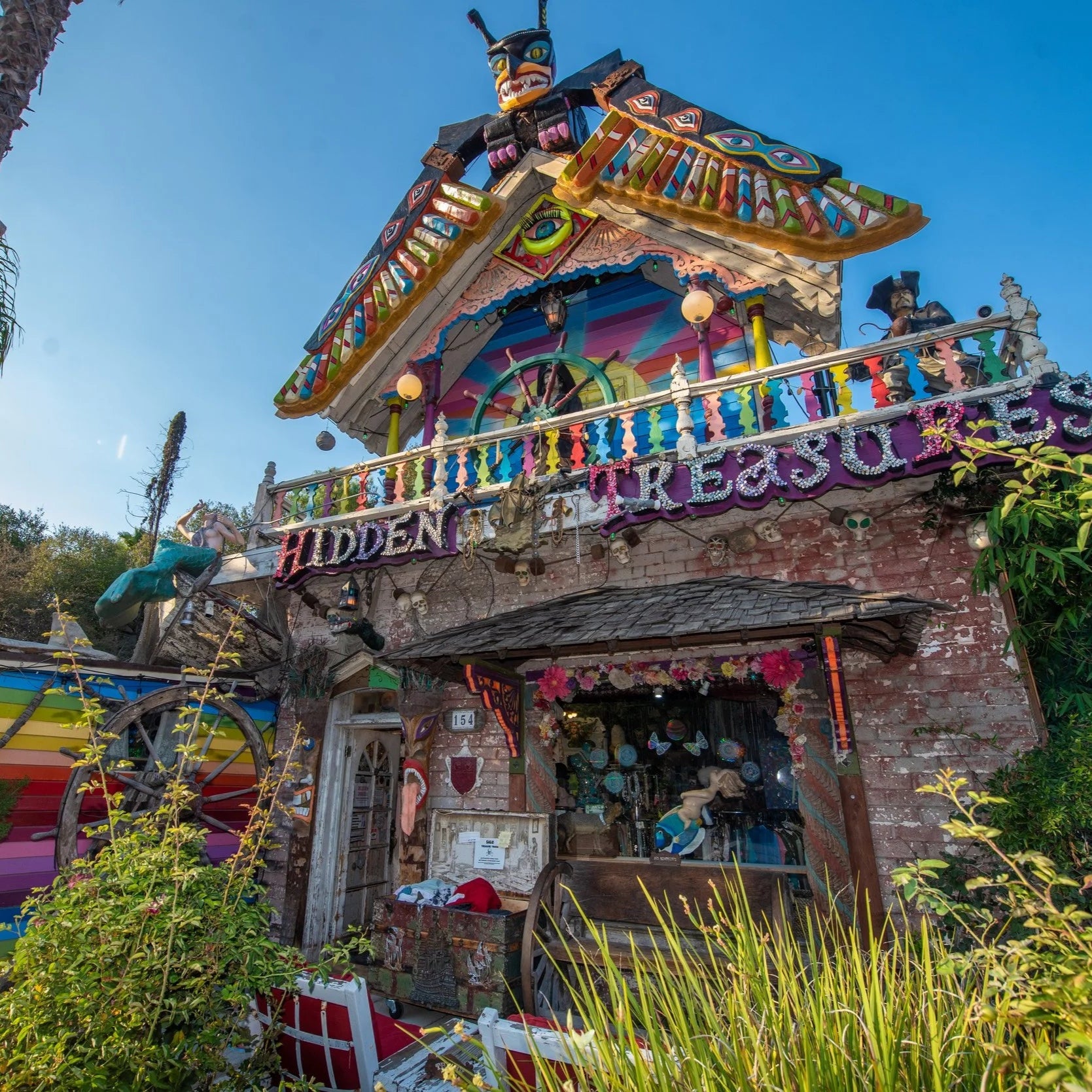 Colorful and intricately designed building with 'Hidden Treasures' sign, surrounded by greenery.