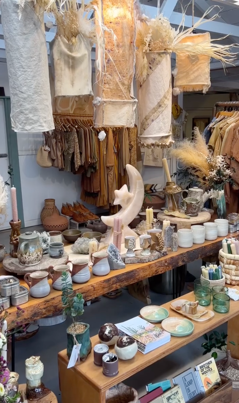 Display of decorative items including pottery, candles, and plants in a store setting.